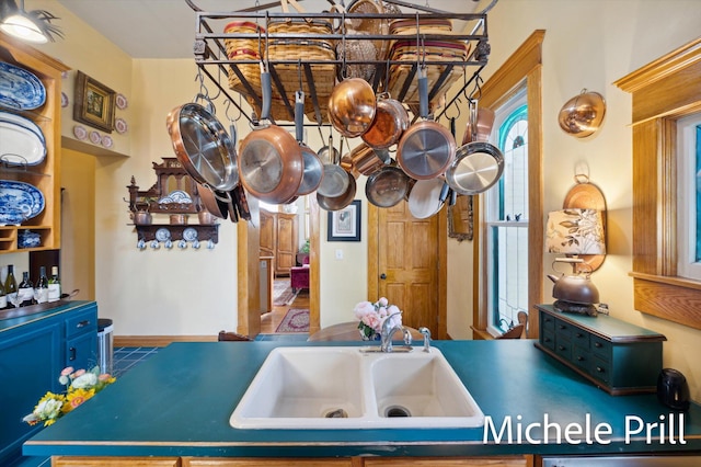 kitchen featuring tile patterned floors, an island with sink, blue cabinets, and sink