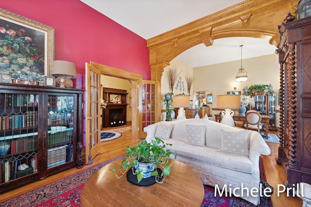 living room featuring french doors, light wood-type flooring, and lofted ceiling