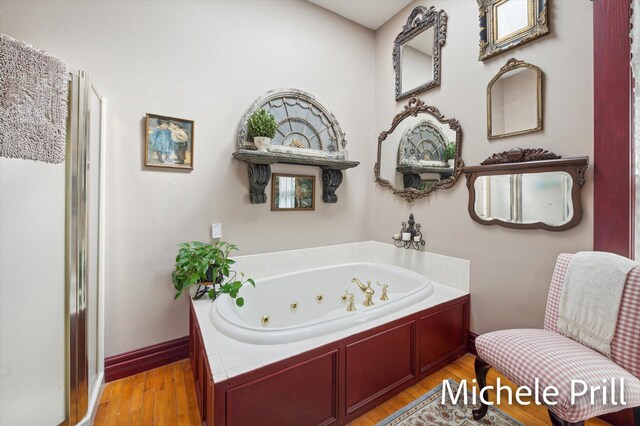 118 E Oliver St, Owosso, MI 48867 - bathroom with a jetted tub, wood finished floors, and baseboards
