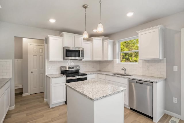 kitchen with white cabinets, light hardwood / wood-style flooring, a kitchen island, and stainless steel appliances