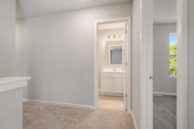 hallway with sink and light colored carpet