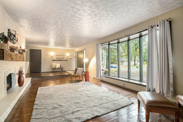 living room with a healthy amount of sunlight, dark hardwood / wood-style flooring, a textured ceiling, and a brick fireplace