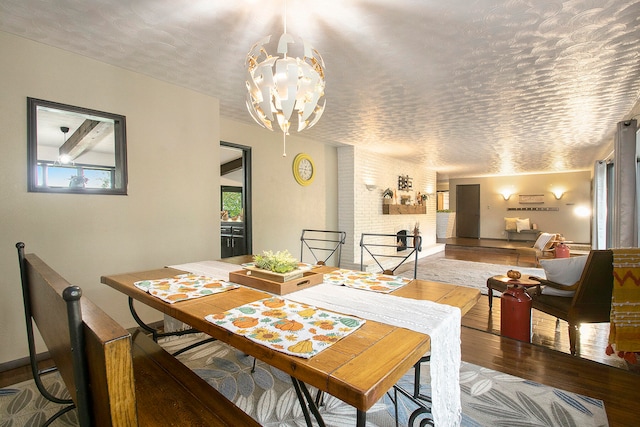 dining space with wood-type flooring, a textured ceiling, and an inviting chandelier