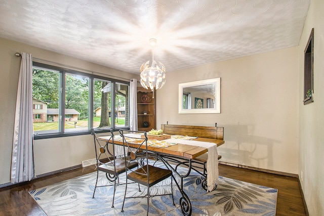 dining room featuring a textured ceiling, dark wood-type flooring, and an inviting chandelier