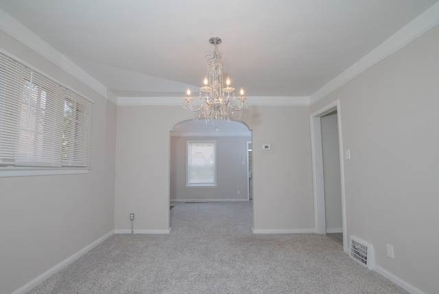 unfurnished room with an inviting chandelier, crown molding, and light colored carpet