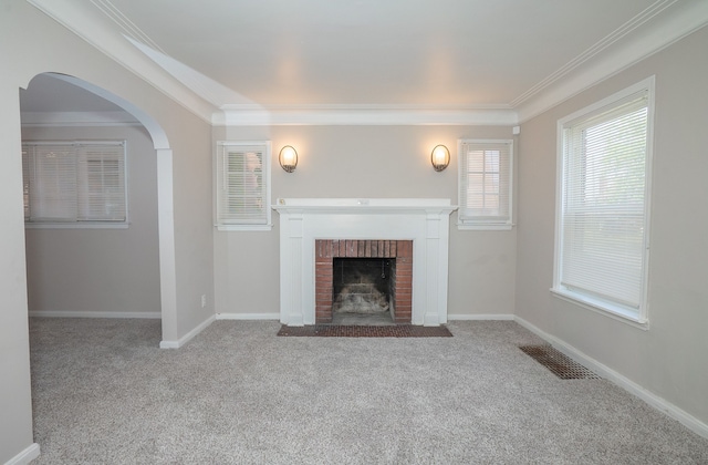 unfurnished living room featuring ornamental molding, light carpet, and a fireplace