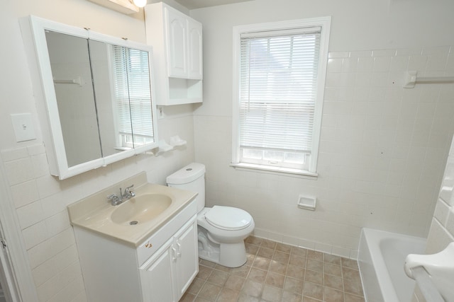 bathroom featuring tile patterned floors, a tub to relax in, toilet, tile walls, and vanity