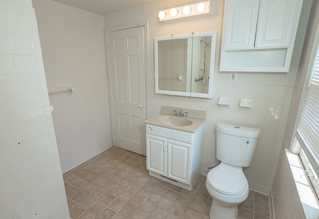 bathroom with vanity, toilet, and tile walls