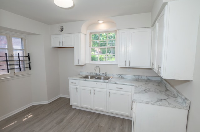 kitchen with light stone counters, sink, light hardwood / wood-style floors, and white cabinets