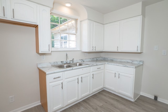 kitchen with white cabinetry, sink, and light wood-type flooring