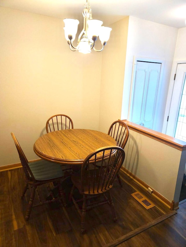 dining area with dark wood-type flooring and a notable chandelier