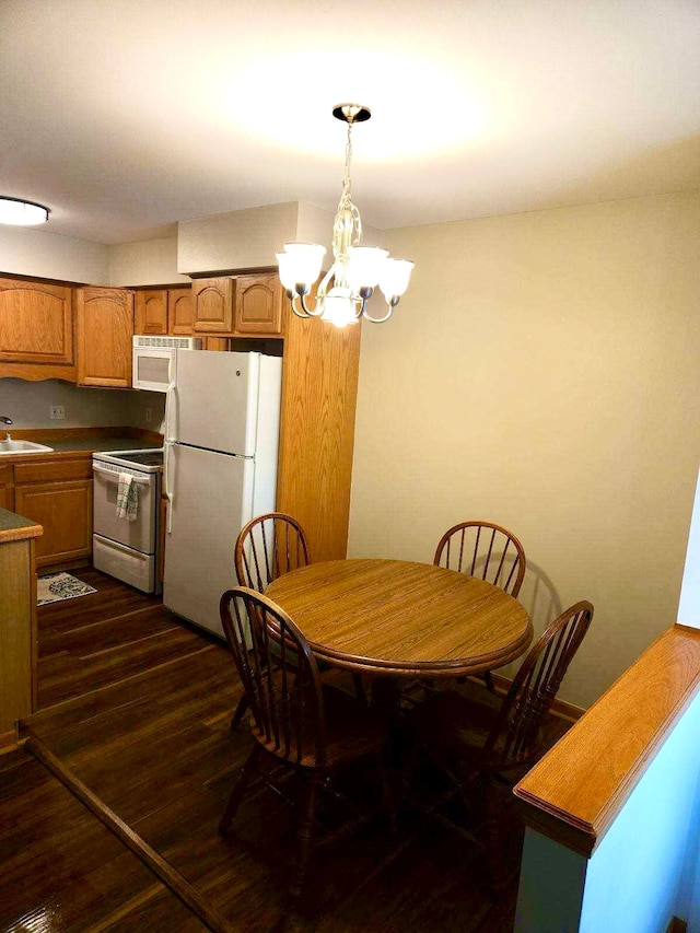 dining area featuring an inviting chandelier, sink, and dark hardwood / wood-style floors