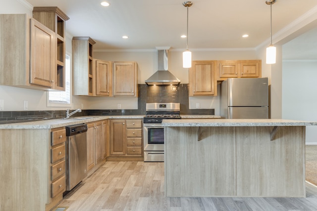 kitchen featuring light brown cabinets, wall chimney exhaust hood, hanging light fixtures, stainless steel appliances, and light wood-type flooring