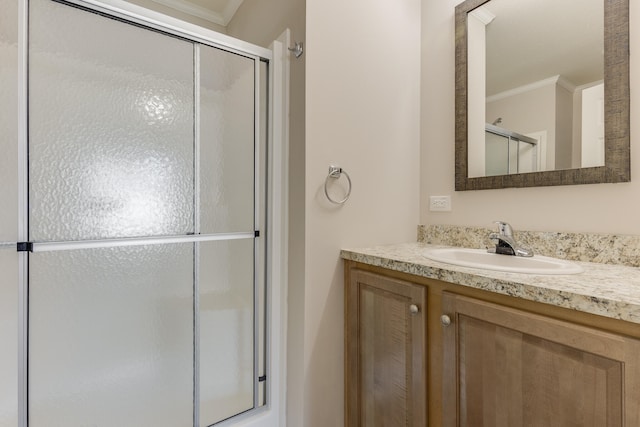 bathroom featuring vanity, a shower with door, and crown molding