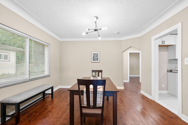 dining area featuring an inviting chandelier, a textured ceiling, and dark wood-type flooring