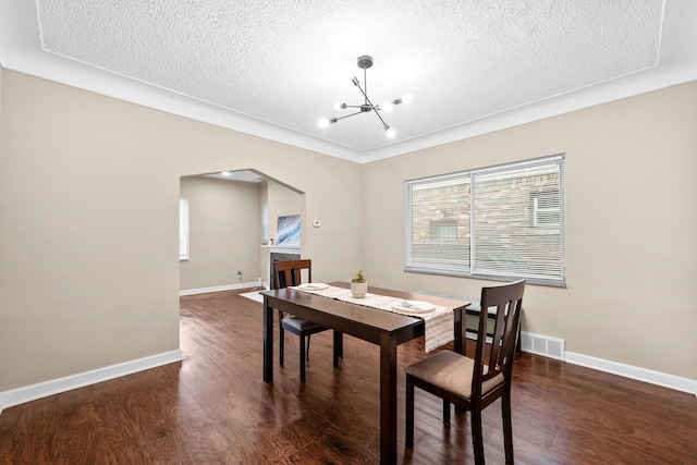 dining area featuring a textured ceiling, an inviting chandelier, and dark wood-type flooring