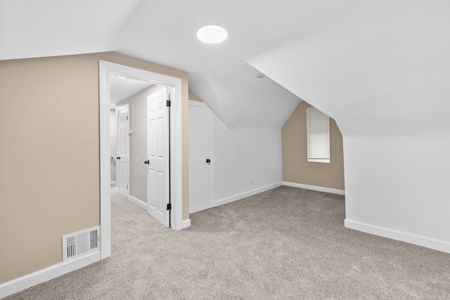 additional living space featuring light colored carpet and lofted ceiling