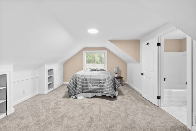 bedroom featuring connected bathroom, light carpet, and lofted ceiling