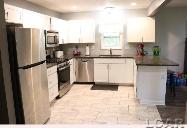 kitchen featuring kitchen peninsula, white cabinetry, sink, and stainless steel appliances