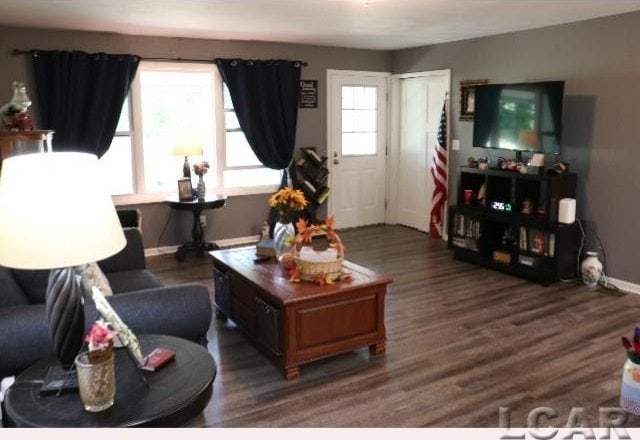 living room with plenty of natural light and dark wood-type flooring