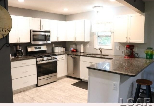 kitchen featuring kitchen peninsula, white cabinetry, sink, and stainless steel appliances