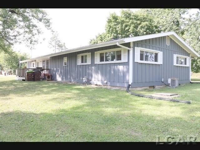 exterior space with a wooden deck, a yard, and cooling unit