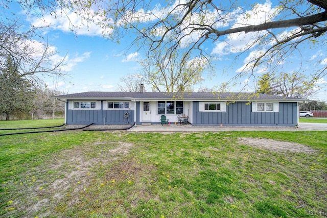ranch-style home with a chimney, a front lawn, a patio area, and board and batten siding