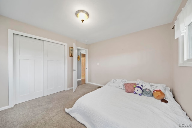 carpeted bedroom featuring baseboards and a closet