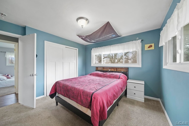 carpeted bedroom featuring baseboards and a closet