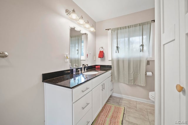 bathroom featuring toilet, vanity, and baseboards