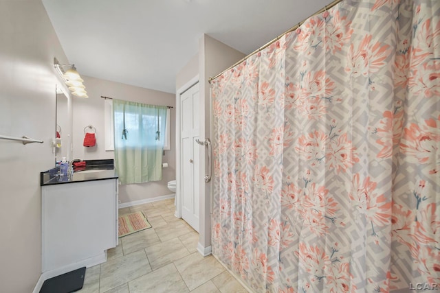 bathroom featuring toilet, vanity, and baseboards