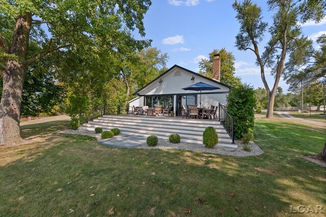 rear view of house featuring a yard and a deck