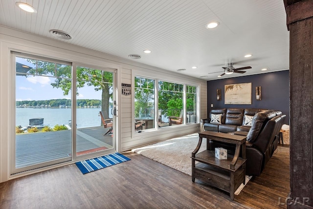 living room featuring dark hardwood / wood-style flooring, ceiling fan, and a water view