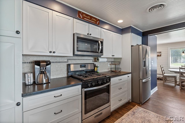 kitchen featuring backsplash, white cabinetry, stainless steel appliances, and dark wood-type flooring