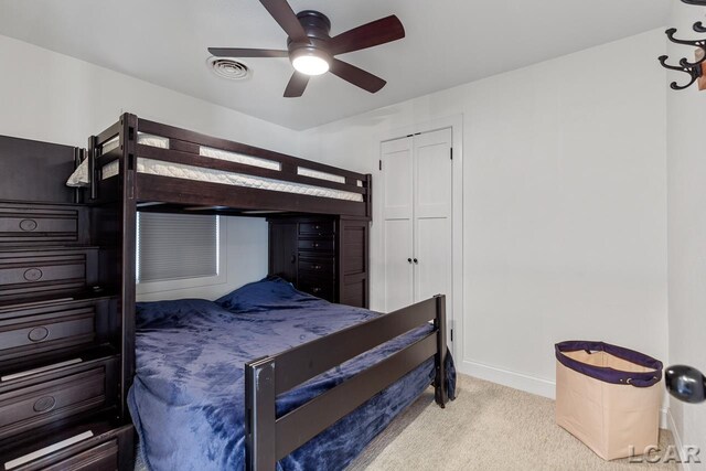 bedroom featuring a closet, light colored carpet, and ceiling fan