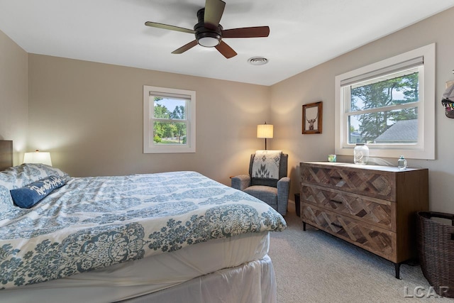 carpeted bedroom featuring multiple windows and ceiling fan