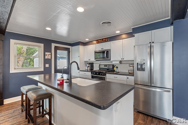 kitchen with white cabinets, sink, stainless steel appliances, and a kitchen island with sink