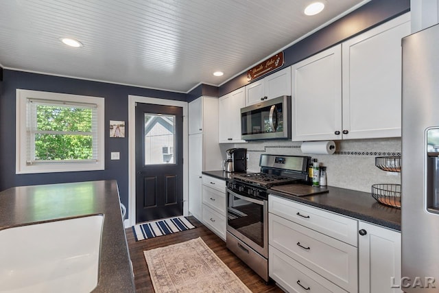 kitchen with backsplash, dark hardwood / wood-style floors, white cabinetry, and stainless steel appliances