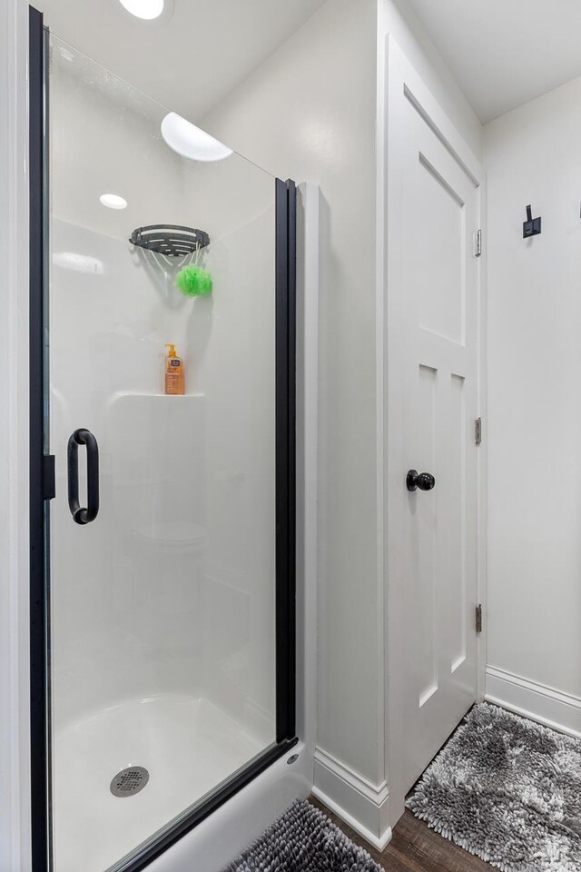 bathroom with wood-type flooring and a shower with door