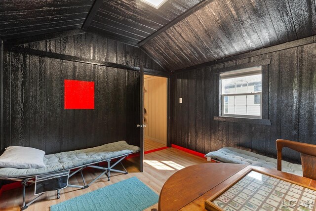 interior space with hardwood / wood-style flooring, vaulted ceiling, and wooden walls