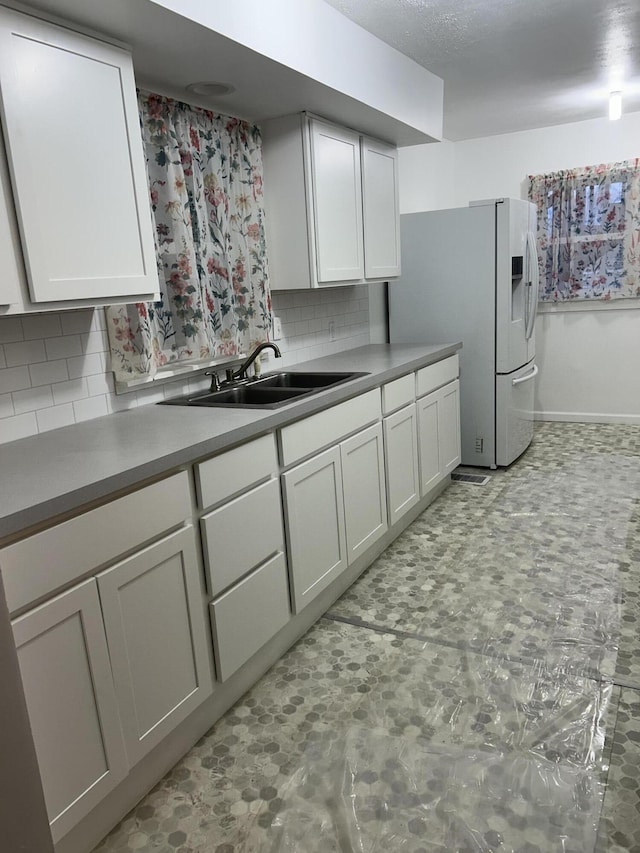 13664 Wabasis Ave NE, Cedar Springs, MI 49319 - kitchen featuring a sink, backsplash, white refrigerator with ice dispenser, white cabinetry, and light countertops