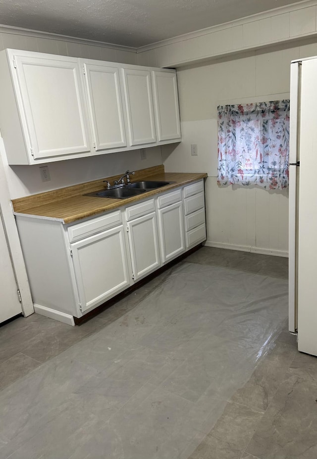 13664 Wabasis Ave NE, Cedar Springs, MI 49319 - kitchen with a sink, freestanding refrigerator, white cabinetry, ornamental molding, and baseboards