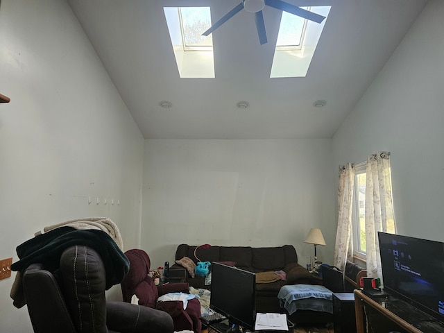 living room with ceiling fan, high vaulted ceiling, and a skylight