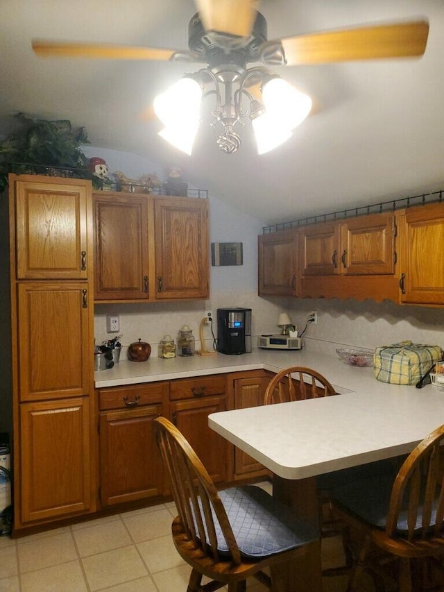 kitchen featuring a breakfast bar, light tile patterned flooring, kitchen peninsula, and lofted ceiling