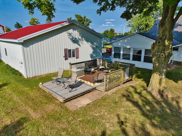 rear view of house featuring a deck and a lawn