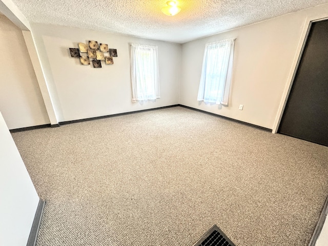 carpeted empty room featuring a textured ceiling