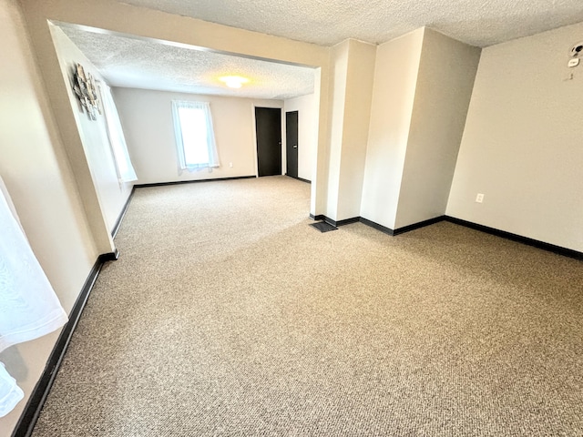 unfurnished room featuring a textured ceiling and light colored carpet