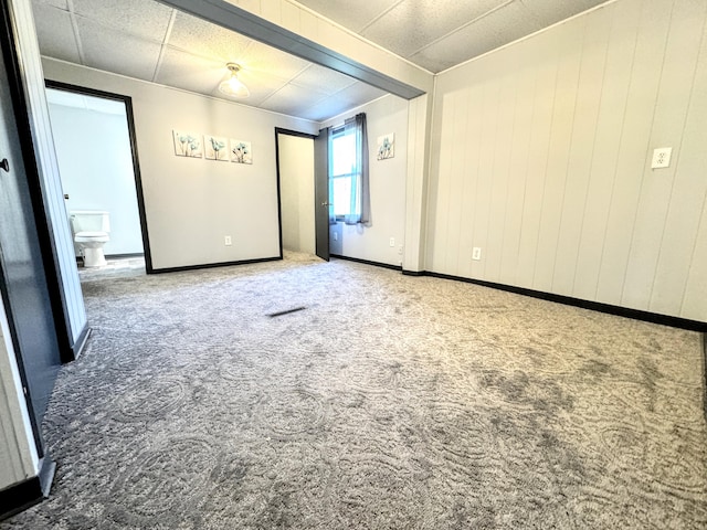 carpeted empty room with a paneled ceiling