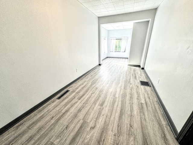 interior space featuring a paneled ceiling and light hardwood / wood-style flooring