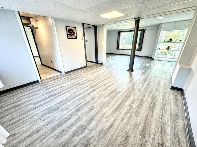 basement with a paneled ceiling and light hardwood / wood-style floors